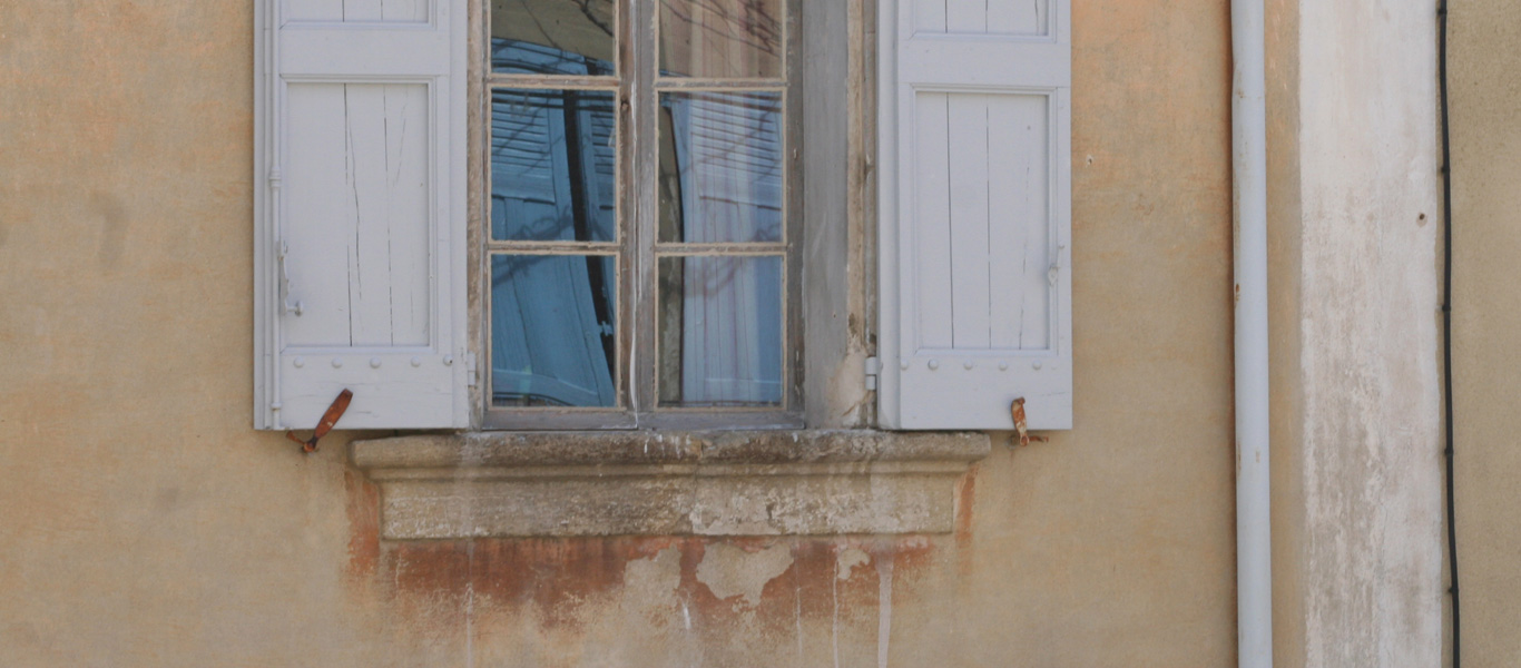 Fensterläden spiegeln sich im Fenster